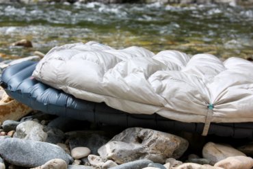 This review photo shows the Therm-a-Rest Vesper Quilt outside on top of a Therm-a-Rest NeoAir UberLite air mattress for backpacking.