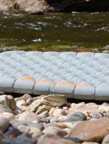 Sea to Summit Ether Light XT Insulated Air Mat inflated on a rocky shoreline near a mountain river.