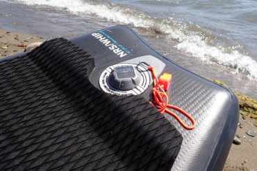 This review photo shows the TRīB airCap Pressure Gauge on an inflatable SUP paddle board on a beach.
