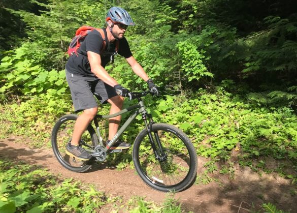 This photo shows the author riding the REI Co-op Cycles DRT 1.2 on a single-track trail.