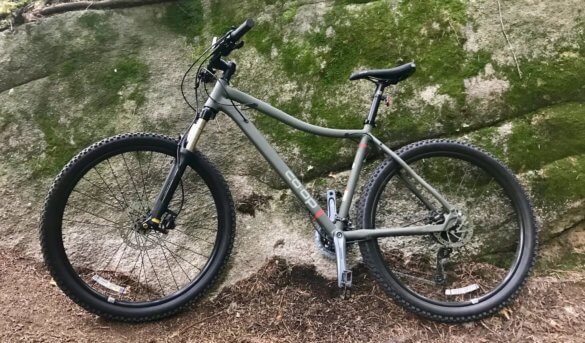 This photo shows the REI Co-op DRT 1.2 mountain bike outside on a trail.