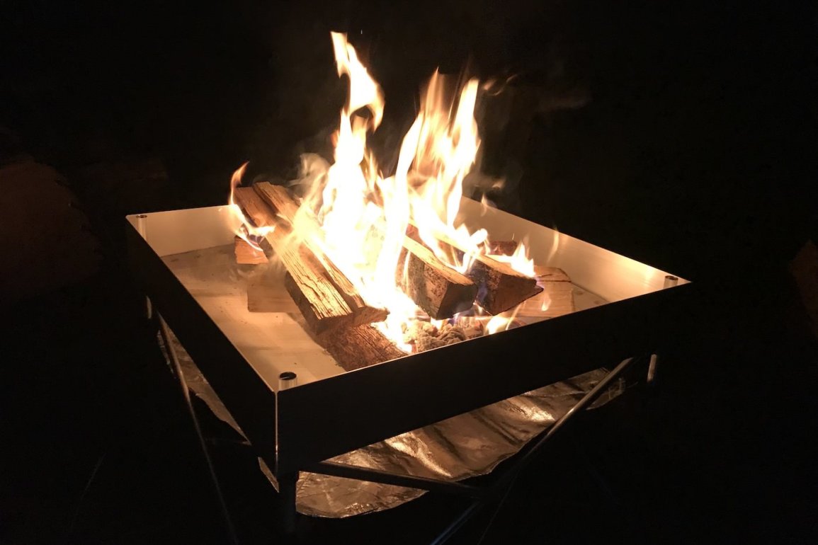 This photo shows the Fireside Outdoor Pop-Up Fire Pit with a campfire in the dark.