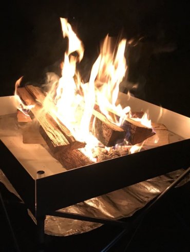 This photo shows the Fireside Outdoor Pop-Up Fire Pit with a campfire in the dark.