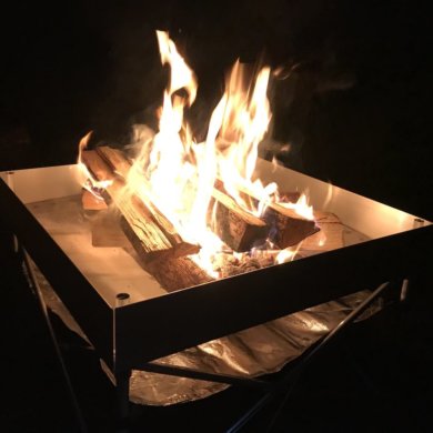 This photo shows the Fireside Outdoor Pop-Up Fire Pit with a campfire in the dark.