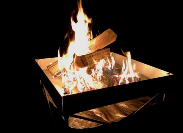 This photo shows the Fireside Outdoor Pop-Up Fire Pit outside with a campfire burning in it.