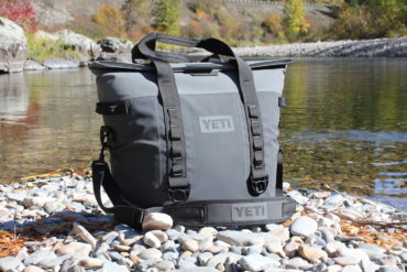 This photo shows the YETI Hopper M30 soft cooler next to a river.