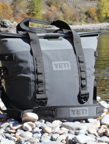 This photo shows the YETI Hopper M30 soft cooler next to a river.
