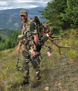 This photo shows a bowhunter with a compound bow and elk antlers in a hunting backpack.