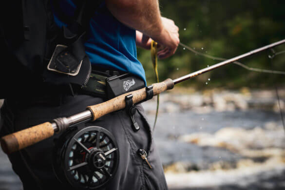 This photo shows the O'Pros 3rd Hand Rod Holder being used by a fly fisherman outside near a river.