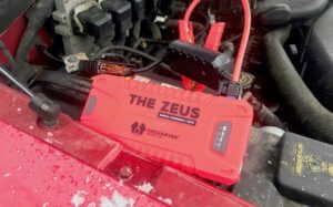 This photo shows The Zeus portable jump starter connected to a vehicle's battery.