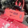This photo shows the Uncharted Supply Co 'The Zeus' portable jump starter attached to a dead auto battery.