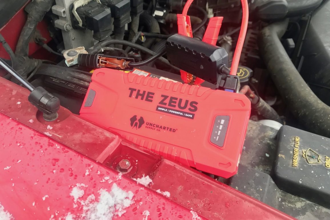 This photo shows the Uncharted Supply Co 'The Zeus' portable jump starter attached to a dead auto battery.