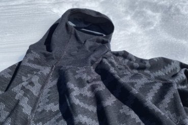 This photo shows the Odlo Natural + Kinship Warm Base Layer Top with Face Mask outside on snow.