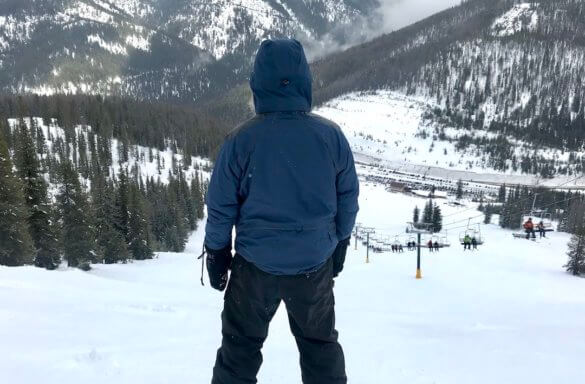 This photo shows a gear tester wearing the Showers Pass Refuge Jacket on a ski and snowboarding hill.