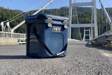 This review photo shows the YETI Roadie 24 cooler on a road near a bridge.