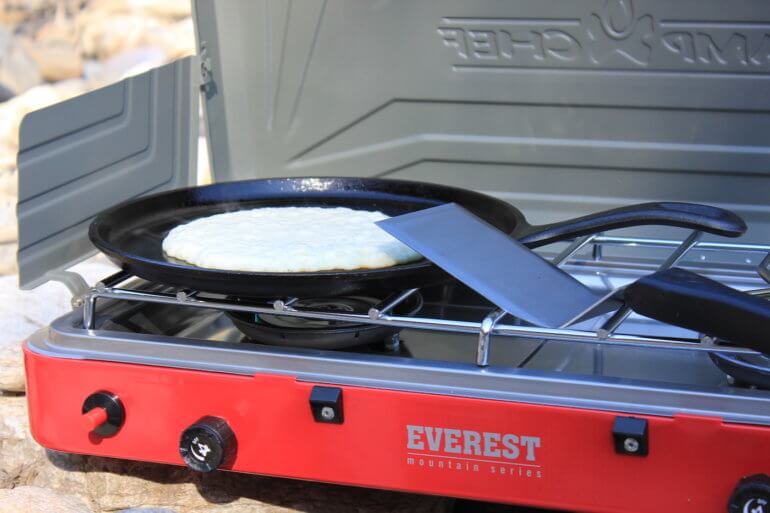 This review photo shows the Camp Chef Everest Two-Burner Camping Stove with a cooking pancake.