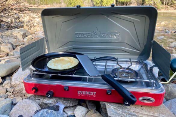 This photo shows This review photo shows the Camp Chef Everest Two-Burner Camping Stove being used to cook a pancake outside.