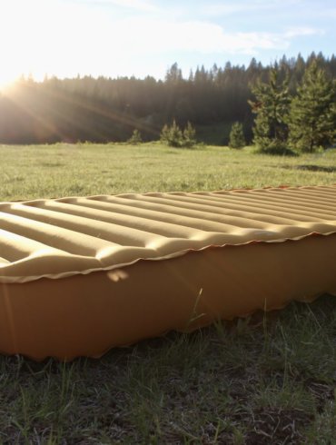 This photo shows the REI Camp Dreamer Insulated Air Sleeping Pad inflated outside at a camping spot.