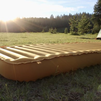 This photo shows the REI Camp Dreamer Insulated Air Sleeping Pad inflated outside at a camping spot.