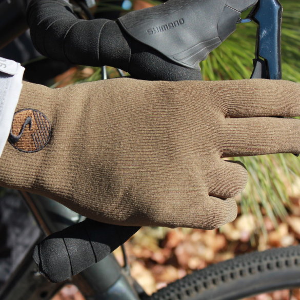 This review photo shows the Showers Pass Crosspoint Waterproof Knit Wool Gloves being worn on a gravel bike by the author.