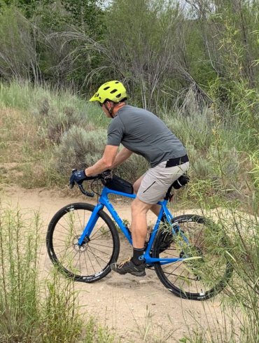 This review photo shows the author testing the Showers Pass Apex Merino Tech shirt while riding a gravel bike.