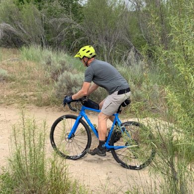 This review photo shows the author testing the Showers Pass Apex Merino Tech shirt while riding a gravel bike.