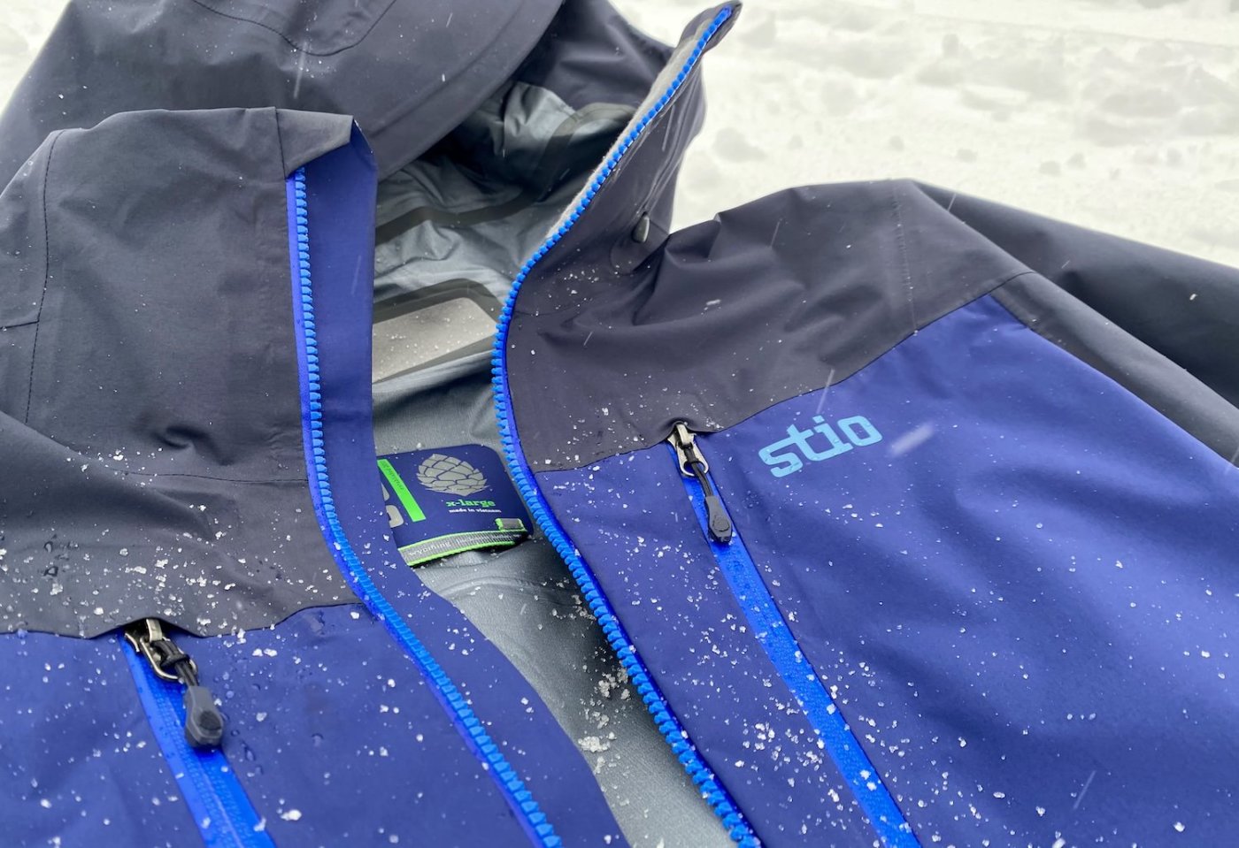 This review photo shows the Stio Objective Pro Jacket outside in a closeup with snow during the testing process.