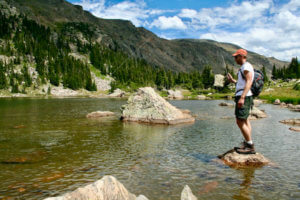 This fly fishing rod and reel combo photo shows a fly fisher fishing on a mountain lake with a fly rod and reel combo.