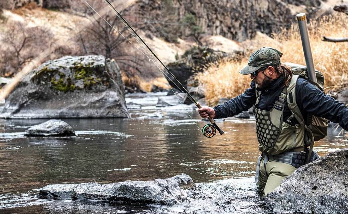 This photo shows a fly fisherman wading in a river while wearing the Simms Flyweight Waders.