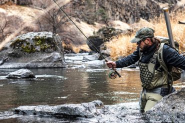 This photo shows a fly fisherman wading in a river while wearing the Simms Flyweight Waders.