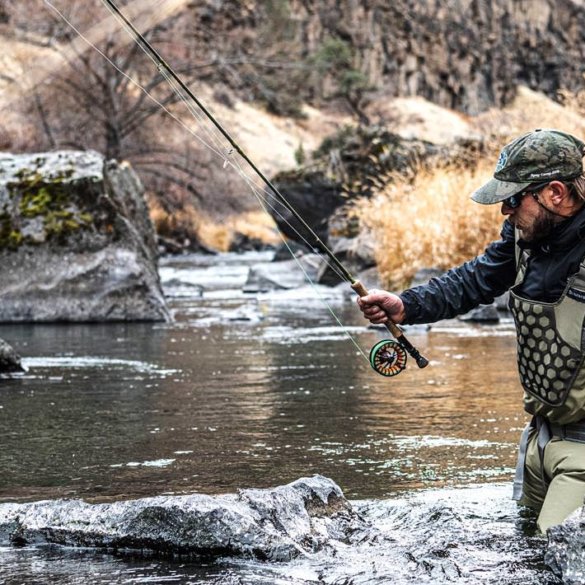 This photo shows a fly fisherman wading in a river while wearing the Simms Flyweight Waders.