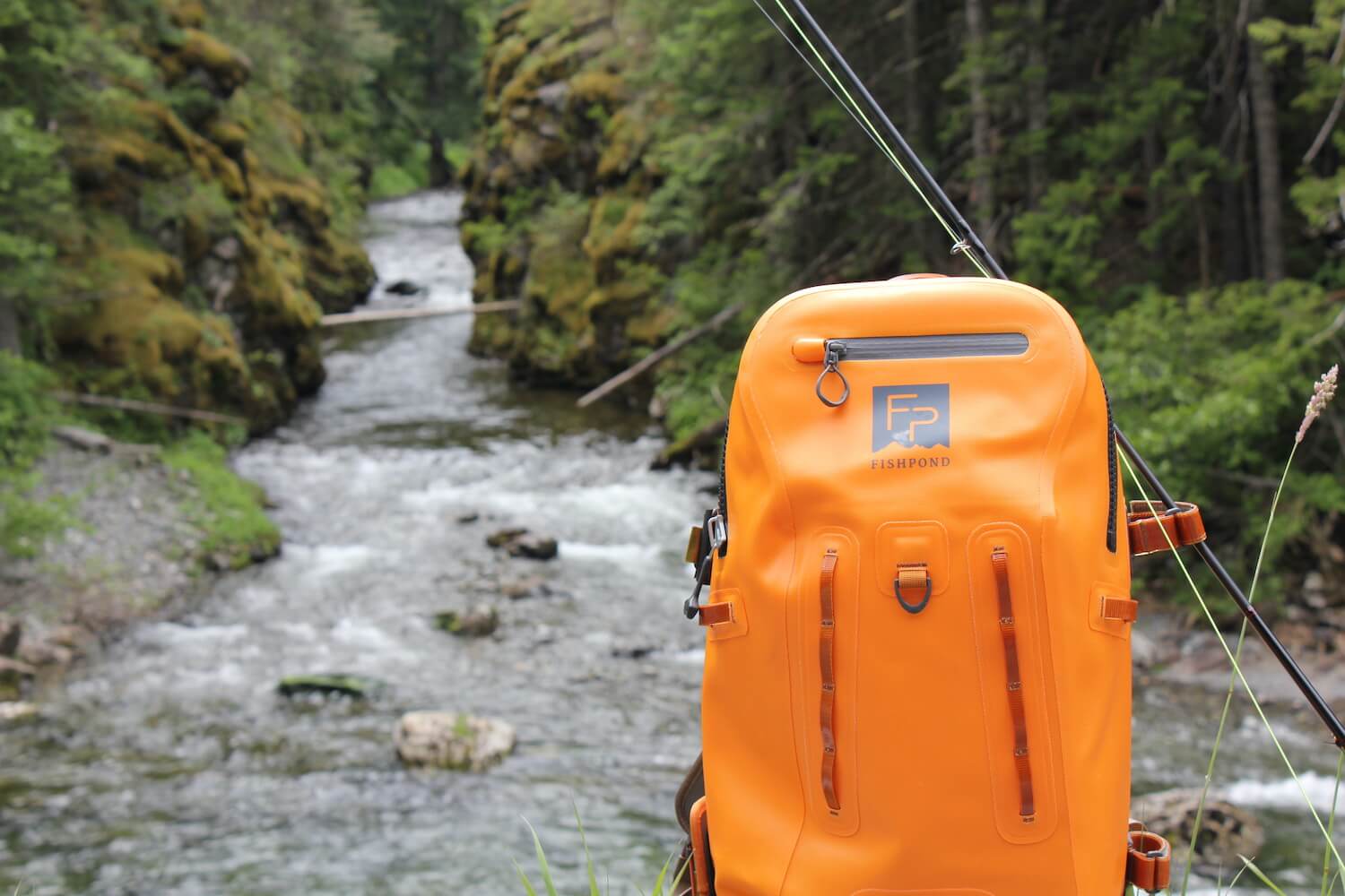 This photo shows a waterproof fishing backpack near a river and stream.