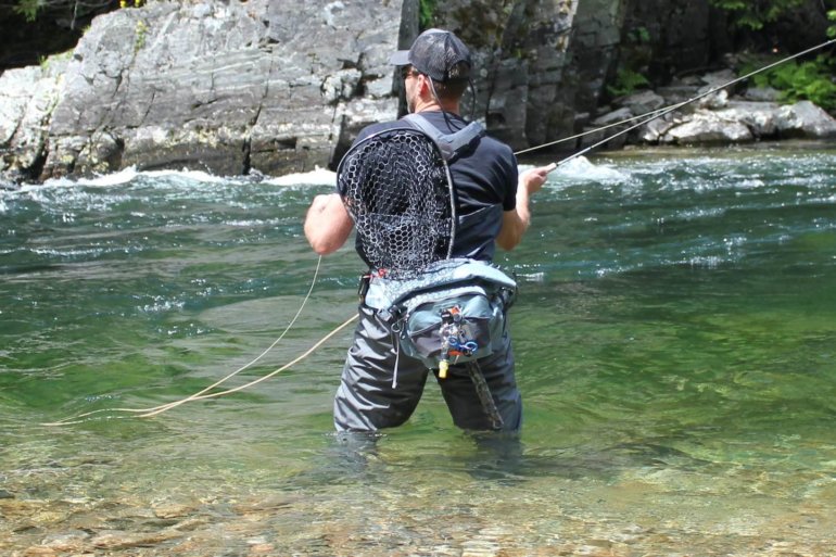 This best fly fishing hip pack photo shows the author testing a fishing hip pack in a river while fly fishing during the review process.