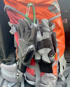 This photo shows the TRUCK M1 Pro Gloves hanging from finger loops on a backpack.