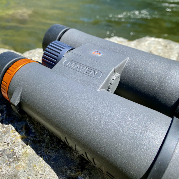 This testing and review photo shows the Maven C.3 10x50 binoculars outside on a rock.