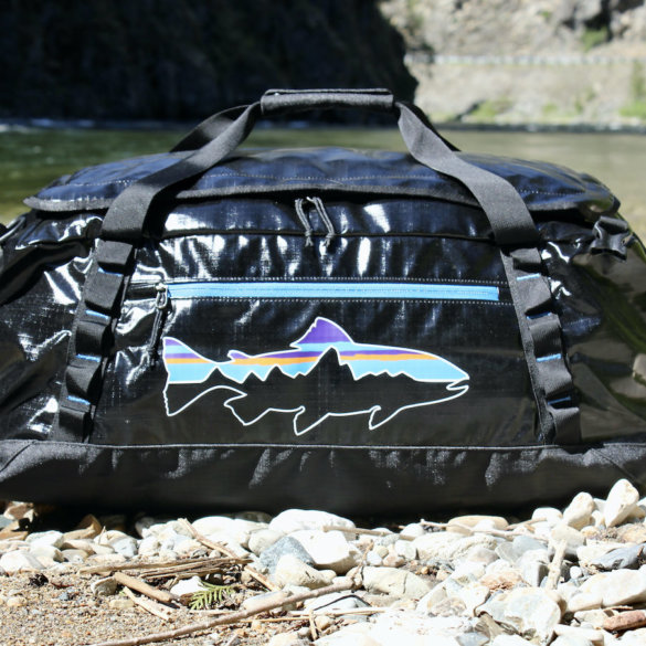 This review photo shows the Patagonia Black Hole Duffel Bag 55L version outside near a river during the testing process.
