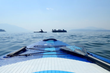 This review photo shows the Outdoor Master Infinite iSUP Chasing Blue paddle board on a lake during the testing process.