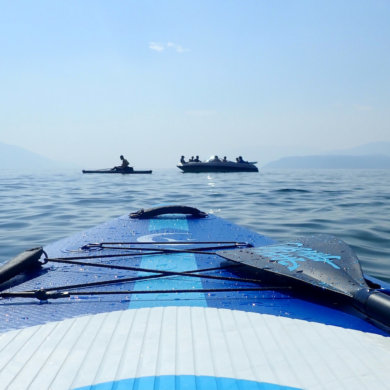 This review photo shows the Outdoor Master Infinite iSUP Chasing Blue paddle board on a lake during the testing process.