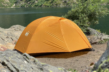 This backpacking tent review photo shows the REI Co-op Half Dome SL 2+ Tent setup near a mountain lake during the testing and review process.
