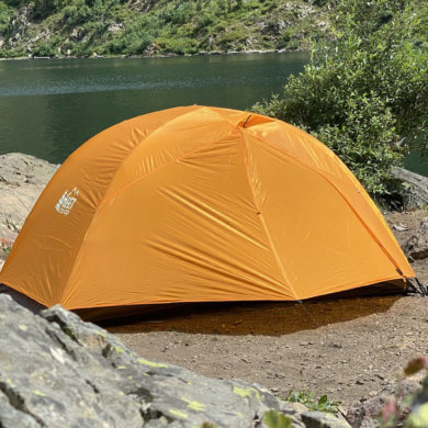 This backpacking tent review photo shows the REI Co-op Half Dome SL 2+ Tent setup near a mountain lake during the testing and review process.