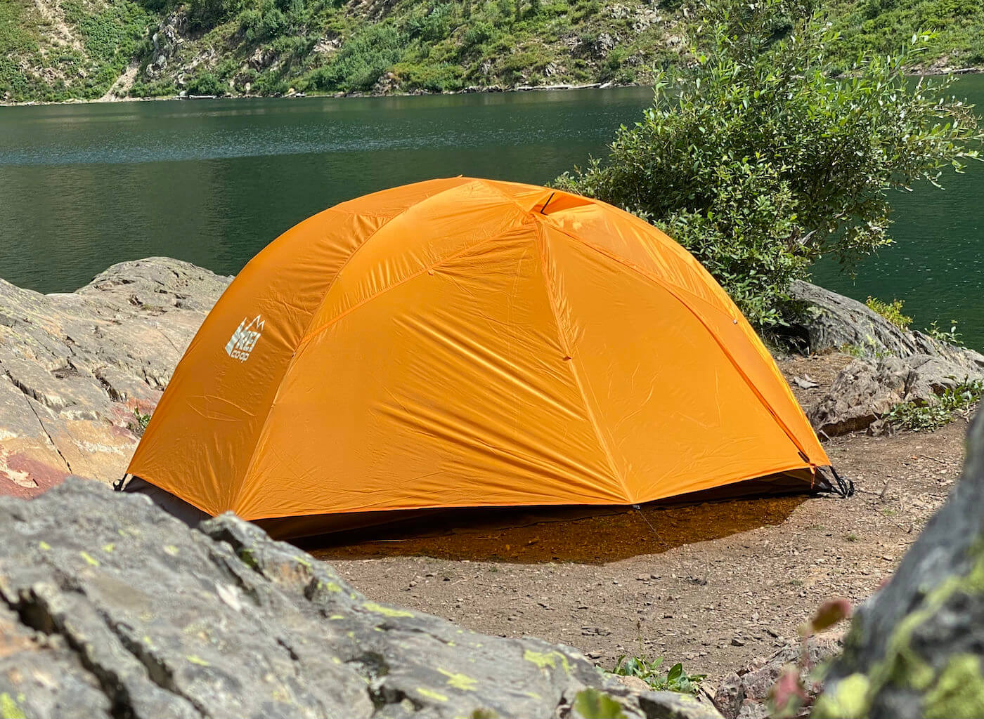 This backpacking tent review photo shows the REI Co-op Half Dome SL 2+ Tent setup near a mountain lake during the testing and review process.