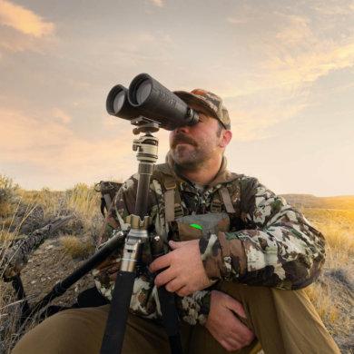 This photo shows a hunter using the Maven C.4 15x56 binoculars outside with a tripod.