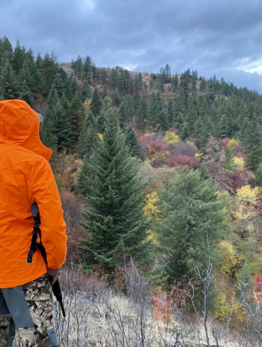 This photo shows the author wearing the L.L.Bean men's Northwoods Rain Jacket while hunting outside in a forest.