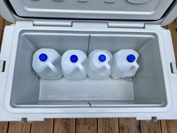 This photo shows the interior of the RTIC 65 QT Hard Cooler with 4 gallon jugs inside to illustrate capacity.