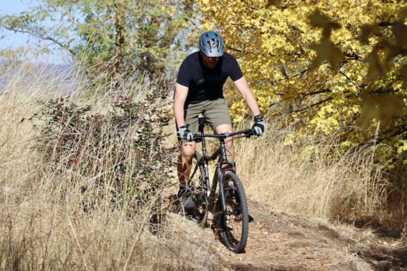 This photo shows the author riding the REI Co-op Cycles DRT 1.1 mountain bike on a trail during the review process.