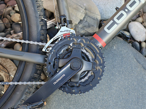 This photo shows a closeup of the Shimano Tourney crankset on the DRT 1.1 bike.