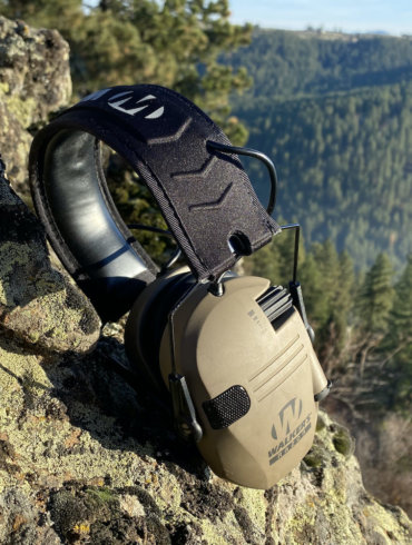 This photo shows the Walker's Slim Digital Razor Muffs outside on a rock in a forest.