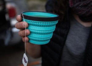 This camping gear gift idea photo shows a person holding the Sea to Summit Cool Grip X-Tumbler with hot tea inside.