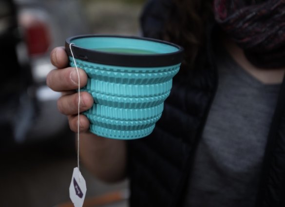 This camping gear gift idea photo shows a person holding the Sea to Summit Cool Grip X-Tumbler with hot tea inside.