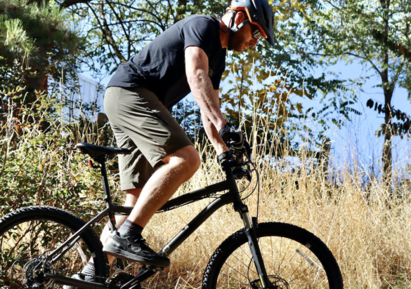 This photo shows the author riding a mountain bike while wear testing the Apex DWR 12" Shorts.